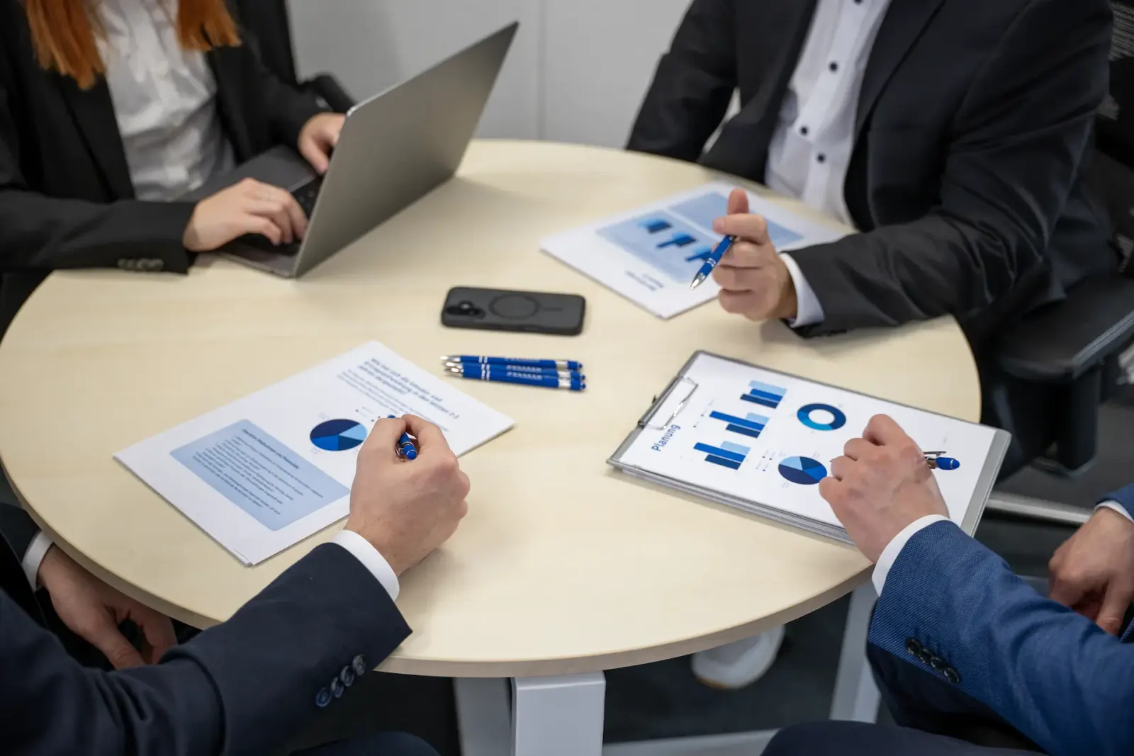 Besprechung am runden Tisch mit Auswertungen, Diagrammen und Laptop